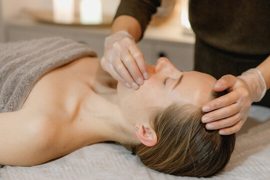 buccal facial massage, close-up, cosmetologist makes woman a procedure on a massage table in a spa salon