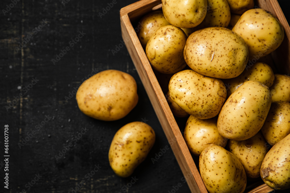 Wall mural Fresh potatoes. On black background.