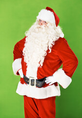 Santa claus, hands and hips in studio portrait for holiday celebration, festive season or gift giving. Father Christmas, face and costume suit for winter vacation fun, on green background for joy