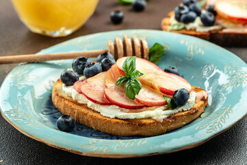 Sweet toast with ricotta cheese, honey and peach on a wooden board, Food recipe background. Close up