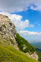 Fototapeta na wymiar steep rocky cliff in the Crimean mountains in Europe against the backdrop of distant hills and a blue sky with clouds