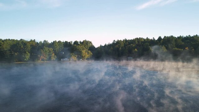 Morning mist rises fron the surface of a lake 