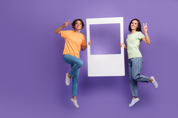 Full body photo of jumping high two sisters showing victory v sign hold window frame zone portrait...
