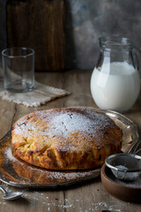 Fresh homemade raisin pie and milk in a glass jug on a rustic table