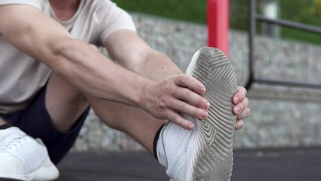 A man feels a sharp pain in his foot and massages his painful leg during an evening workout. Sports and injury concept.