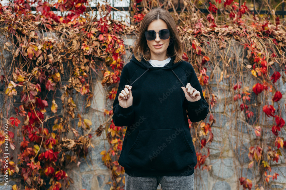 Wall mural Young woman in glasses and black hoodie - Wall murals