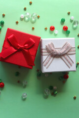 Two small presents and colorful beads on green background. Top view.