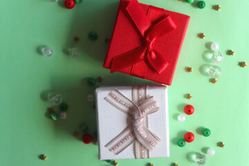 Two small presents and colorful beads on green background. Top view.