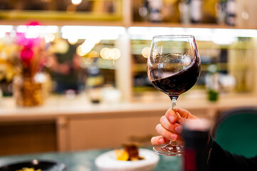 Young man hand holding a glass with red wine in a restaurant