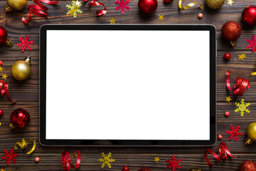 Christmas online shopping from home tablet pc with blank white display top view. Tablet with copy space on colored background with Christmas decorations balls,. Winter holidays sales background - obrazy, fototapety, plakaty