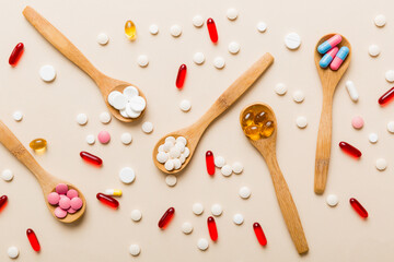Vitamin capsules in a spoon on a colored background. Pills served as a healthy meal. Red soft gel vitamin supplement capsules on spoon
