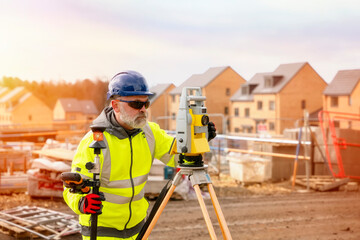 Surveyor builder site engineer with theodolite total station at construction site outdoors during...