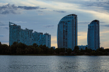 Picturesque landscape view of three high-rise buildings near Dnieper river. Obolon neighborhood in Kyiv. Colorful evening sky