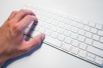 Hand on white computer keyboard