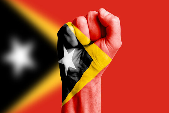 Man hand fist of EAST TIMOR flag painted. Close-up.