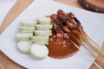 chicken satay on a white plate with peanut sauce