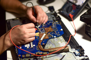 The repairman uses both hands and a meter cable to look for faults on the motherboard. Find the IC...