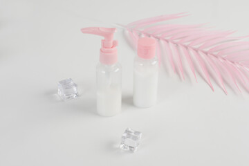 bottles with a dispenser for shampoo, soap. Set of two pink jars for use on a travel on soft white background. Beauty cosmetics glassbottle, branding mock up. Toiletries, shampoo, lotion, shower gel