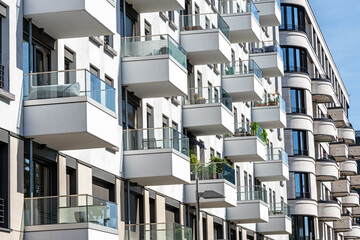 The facade of a white modern apartment building with many small balconies, seen in Berlin, Germany