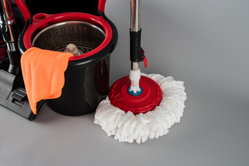 Cleaning concept mop and bucket, vacuum cleaner. Cleaning products and spin mop with red details on...
