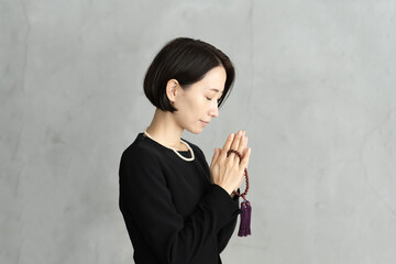 葬儀で手を合わせて祈る女性