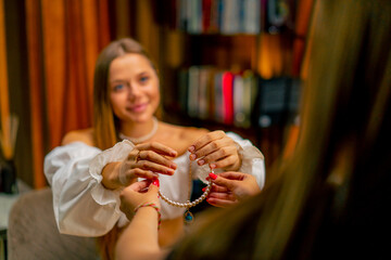 beautiful young needlewoman gives a custom-made pearl necklace to a customer jewelry crafting hobby...