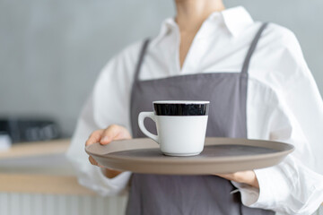 コーヒーを運ぶカフェ店員