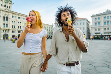 Two lovers hold hands while eating ice cream together in the city center