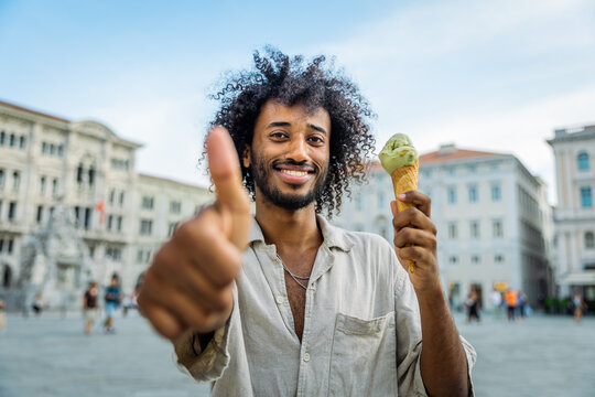 A man is happy and shows a thumbs up while eating ice cream