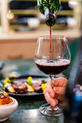 Waiter pouring red wine in glasses for wine on the table in restaurant