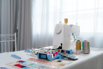 Sewing machine and accessories on the table for the work of a bridal dress tailor