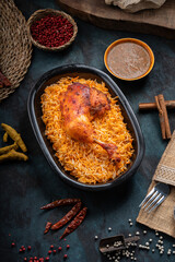 Mandi rice dish with grilled chicken meat and spices on a dark green background