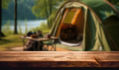 Selbstklebende Fototapeten Wooden table top on blur tent camping travel tent and grass field.Fresh and Relax concept.For montage product display or design key visual layout.View of copy space. © escapejaja