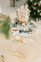 Cake with cookies stars Christmas balls and gold gift with bow on the kitchen table