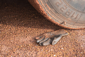 A construction worker rubber glove is placed on dirt ground under the heavy vehicle wheel road at...