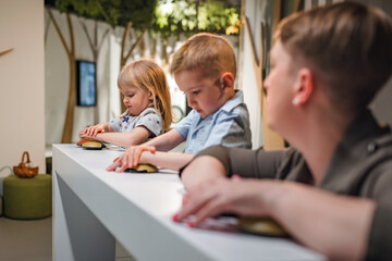 Woman talking with her toddler daughter and son during an interesting natural history museum visit. Family time and childhood education concepts.