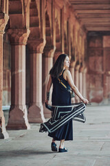 East asian woman in black dress dancing with translucent scarf among columns of ancient indian temple, touristic walking in Taj Mahal of attractive happy young girl, joyful tourism in India