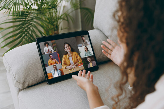 Cropped close up woman lay down on grey sofa couch leading video conference call with diverse group of stay at home hotel flat rest relax spend free spare time in living room indoor. Lounge concept.