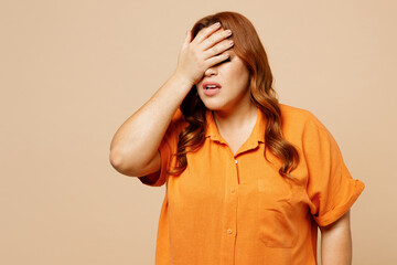 Young sad ginger chubby overweight woman she wear orange shirt casual clothes put hand on face...