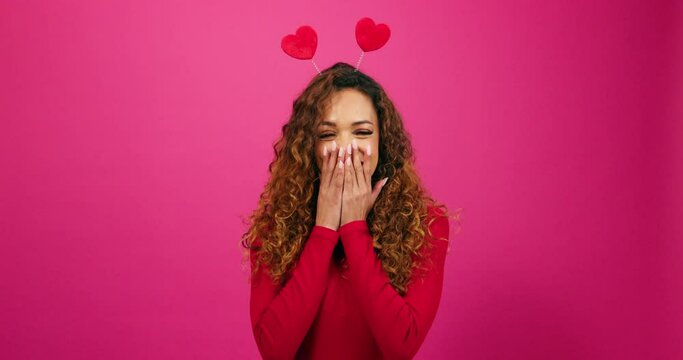 Coy and flirty young woman giggles at secret admirer, Valentines Day studio pink