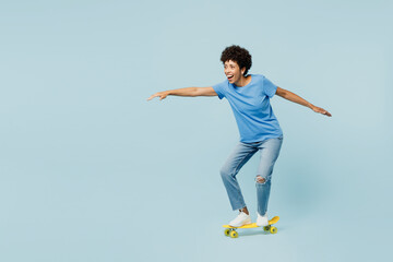 Full body side profile view young woman of African American ethnicity wear t-shirt casual clothes riding skateboard pennyboard isolated on plain pastel light blue cyan background. Lifestyle concept. © ViDi Studio