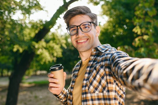 Close up young man wear casual clothes doing selfie shot pov mobile cell phone drink coffee walk rest relax in city park go down alley sunshine lawn outdoors on nature Urban lifestyle leisure concept