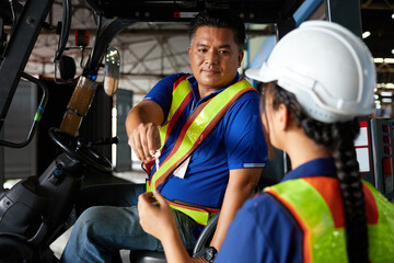 worker giving forklift vehicle key to coworker in the factory