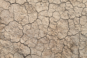 Top view of abstract, cracked, brown earth resembling the surface of Mars or the moon, a textured topography portraying the beauty of desolation