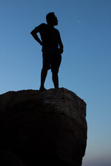 single man standing on the top of the rock or mountain and view the sunset with blue sky on the background