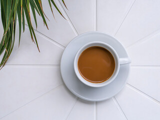 Top down view of a porcelain cup with coffee on a round, white table.