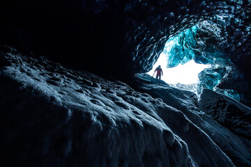 Adventurer discovering the inside of an ice cave in Iceland - obrazy, fototapety, plakaty
