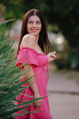 Beautiful woman in pink dress posing at yucca plant