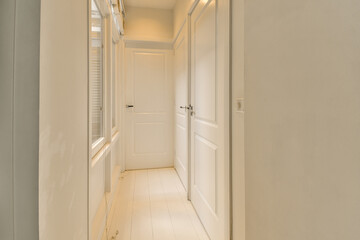 a long hallway with white walls and wood flooring on either side by side, leading to the other rooms