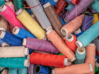 Many colorful sewing threads on spools 